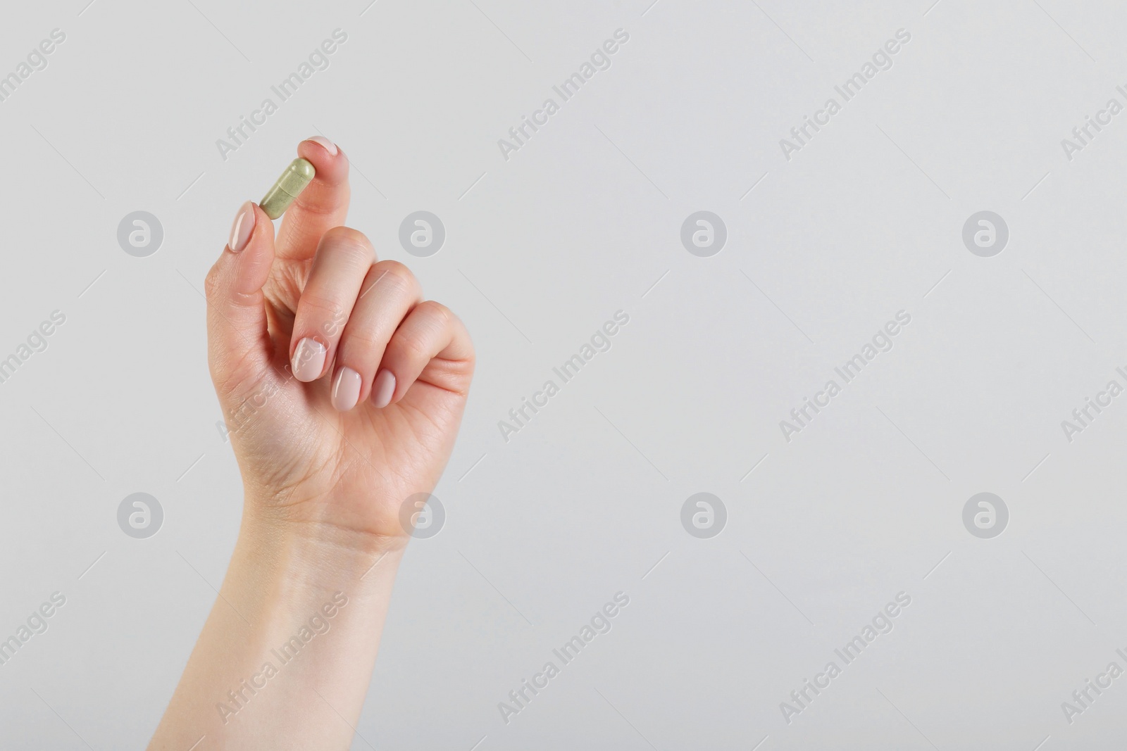 Photo of Woman holding vitamin capsule on grey background, closeup with space for text. Health supplement