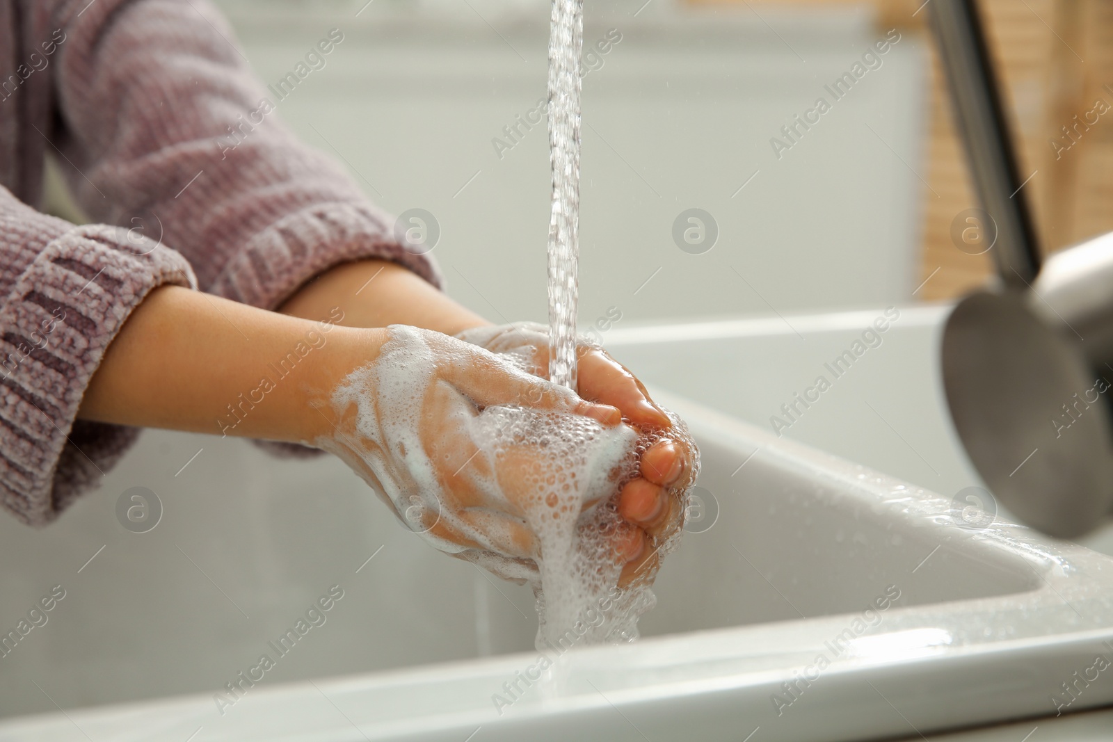 Photo of Little girl washing hands with liquid soap at home, closeup