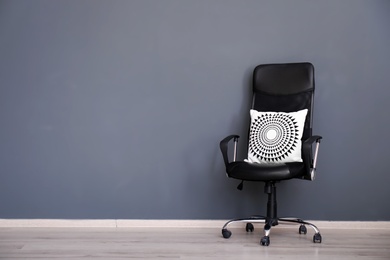 Photo of Leather armchair with soft pillow near grey wall