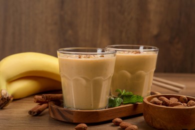 Photo of Tasty banana smoothie with almond and cinnamon on wooden table