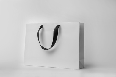 Paper shopping bag with ribbon handles on white background. Mockup for design