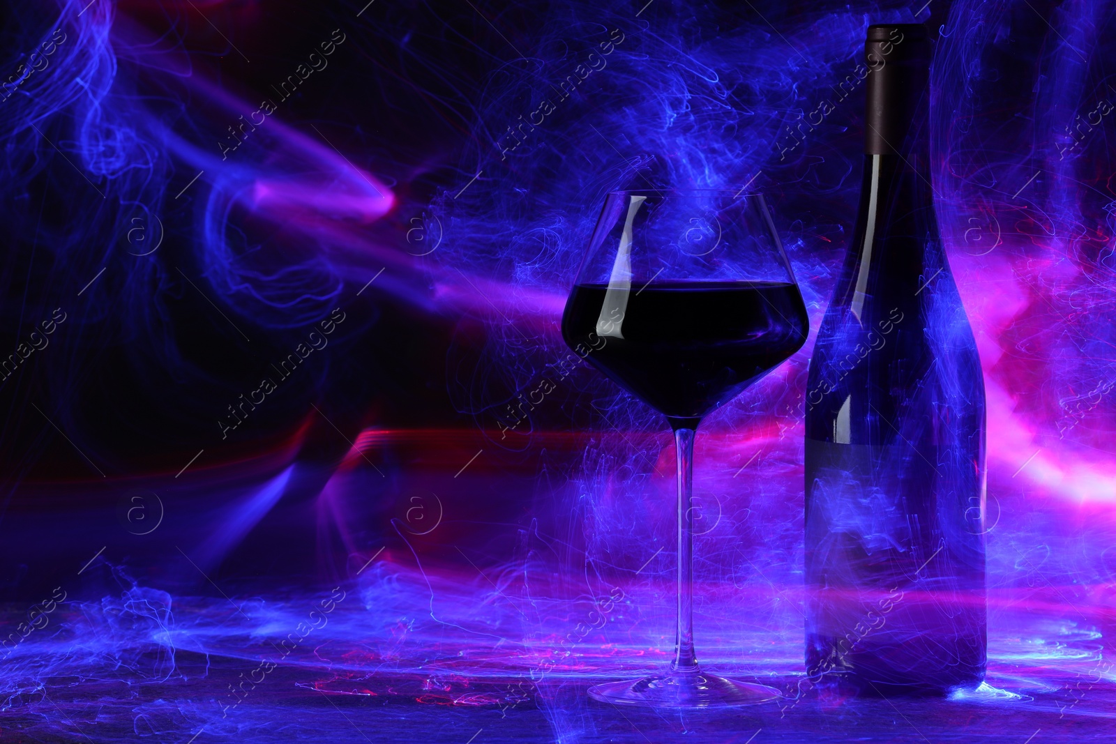 Photo of Red wine in glass and bottle in neon lights, space for text