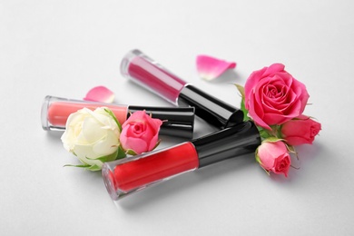 Photo of Lip glosses and flowers on light background