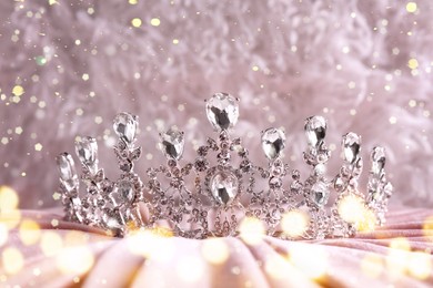 Image of Beautiful silver tiara with diamonds on pink cloth, bokeh effect