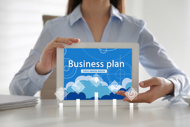 Woman holding tablet with inscription BUSINESS PLAN on screen, closeup 
