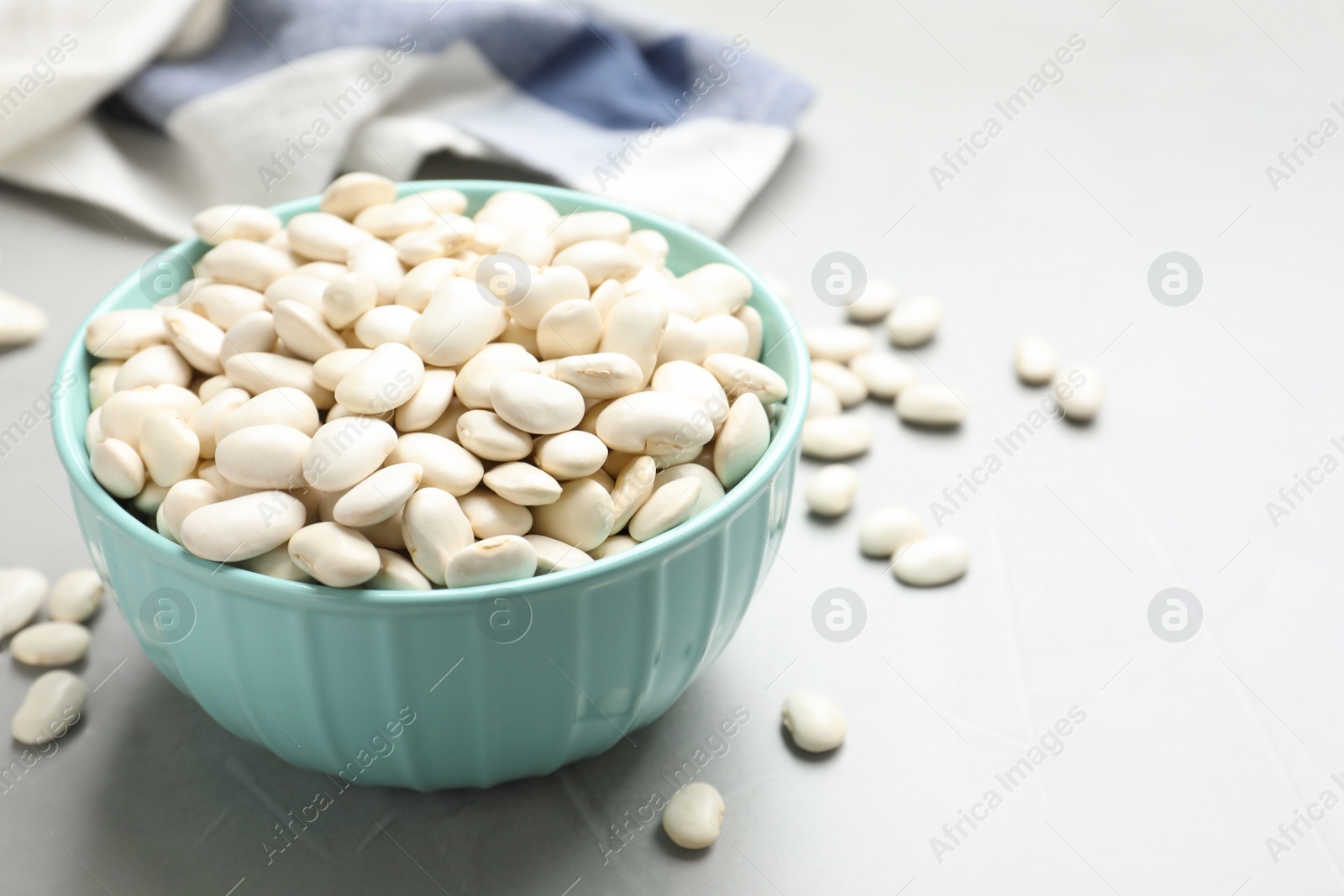 Photo of Raw white beans on light grey table, closeup. Space for text