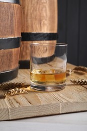 Photo of Wooden barrels, glass of tasty whiskey and spikes on white table