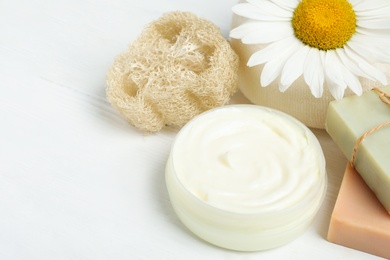 Composition with chamomile flower and cosmetic products on white wooden table, closeup