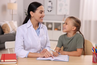 Dyslexia treatment. Therapist working with girl at table in room