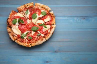 Photo of Delicious Caprese pizza on blue wooden table, top view. Space for text