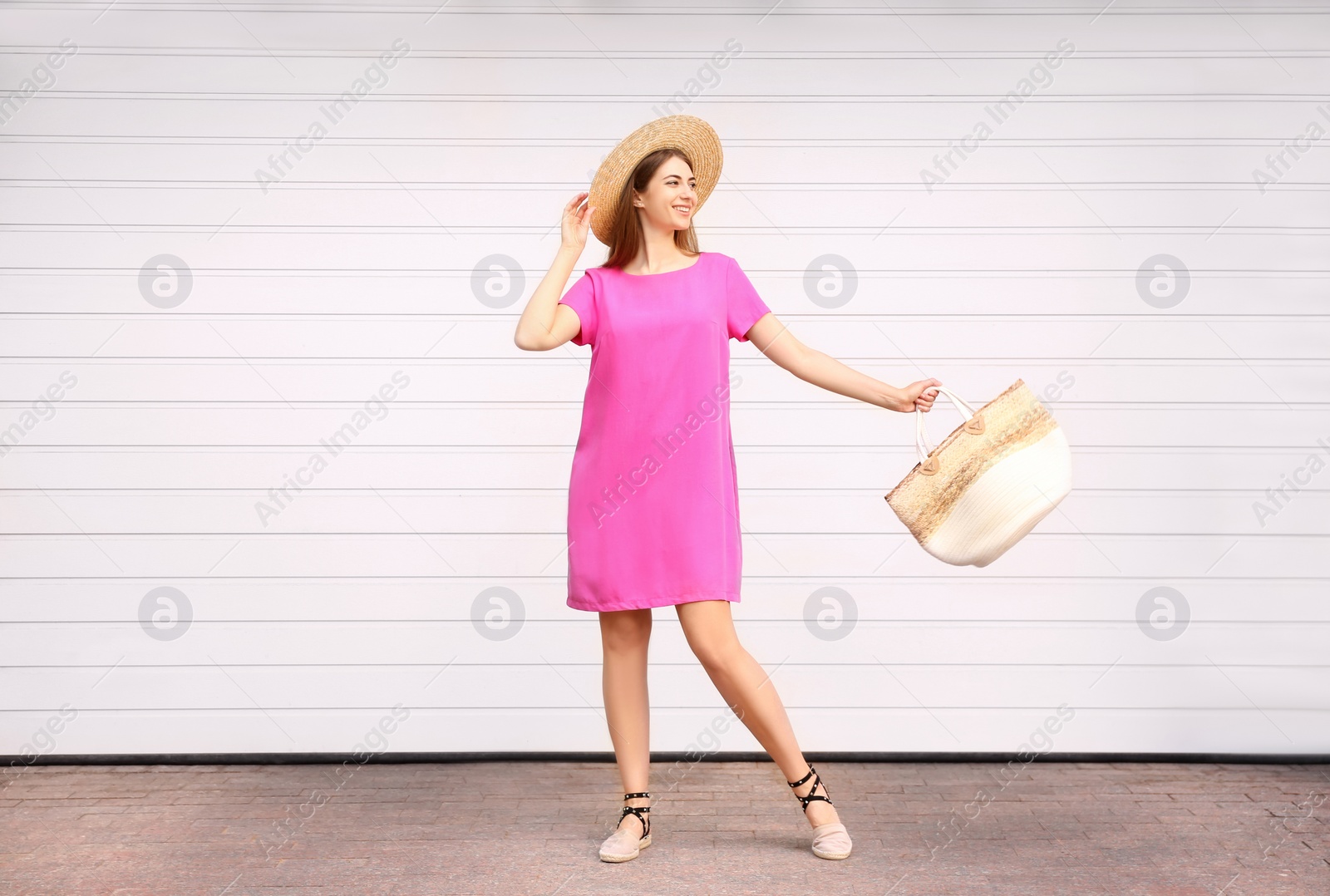 Photo of Beautiful young woman with stylish bag near white wall outdoors