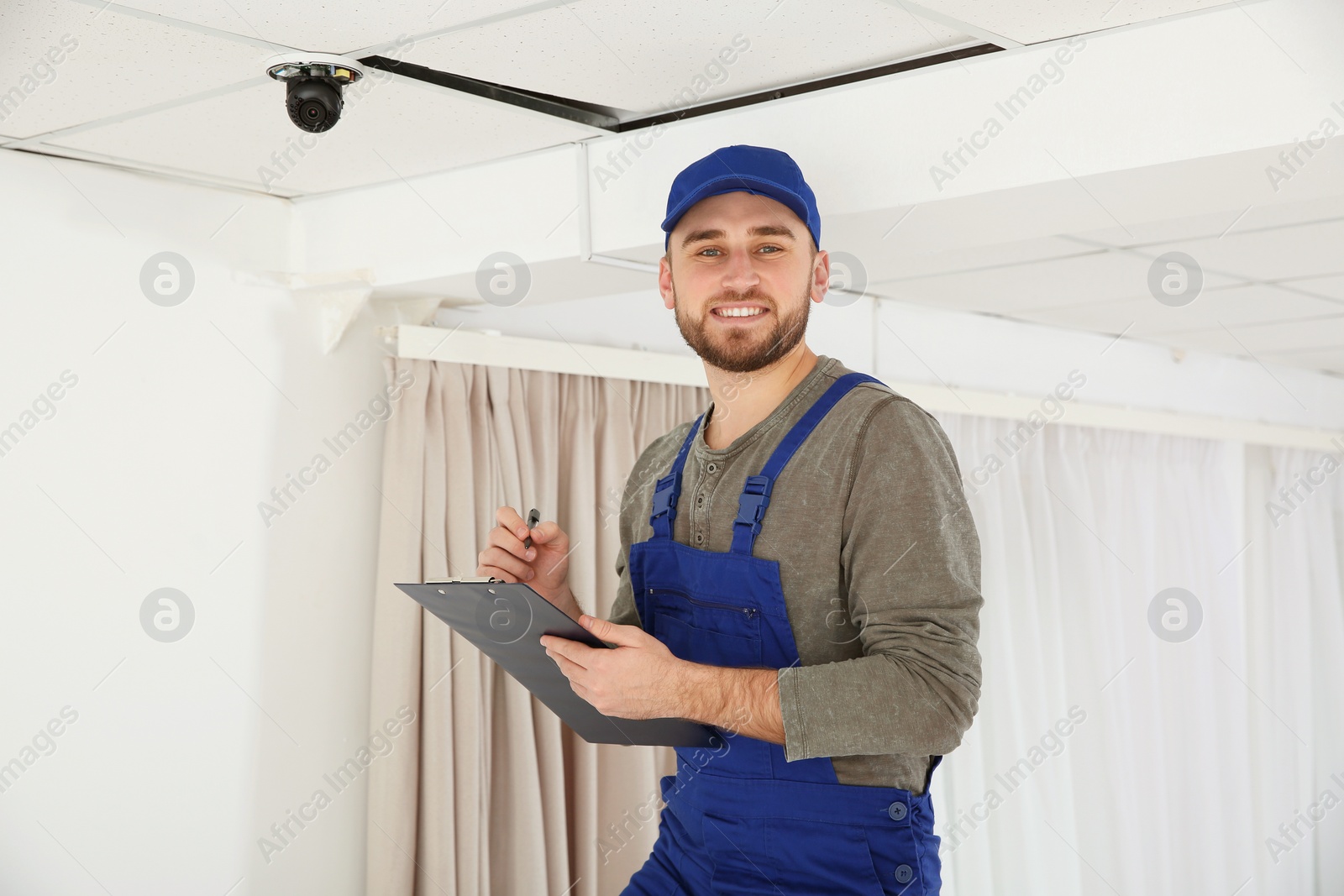 Photo of Electrician with clipboard checking camera in light room