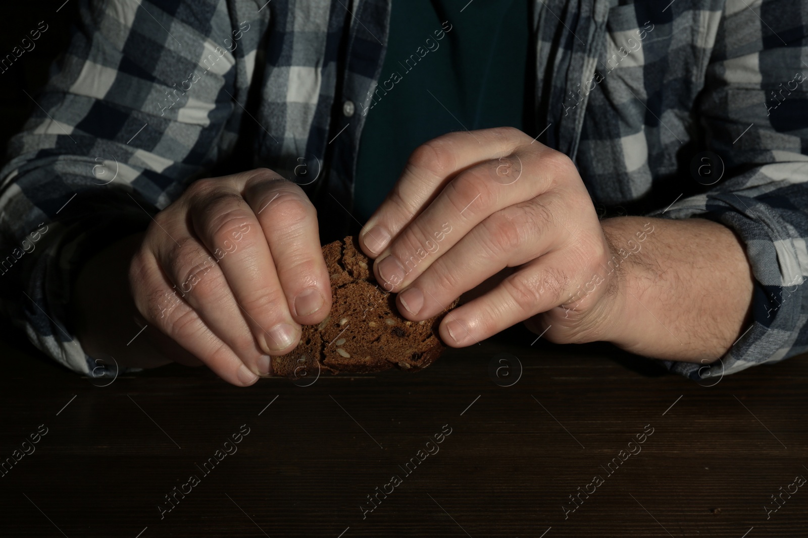 Photo of Poor senior man with bread at table, closeup