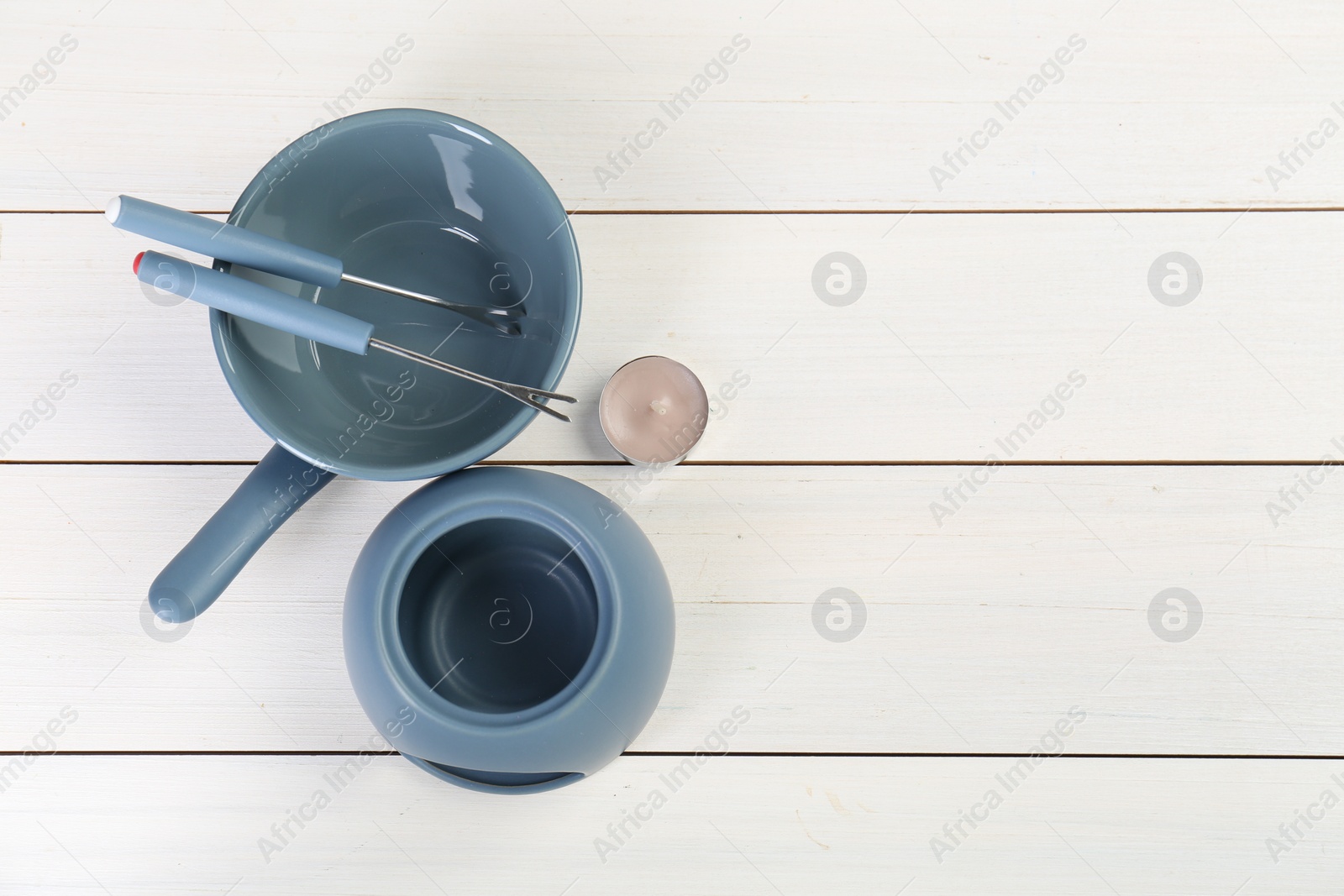 Photo of Fondue set on white wooden table, flat lay. Space for text