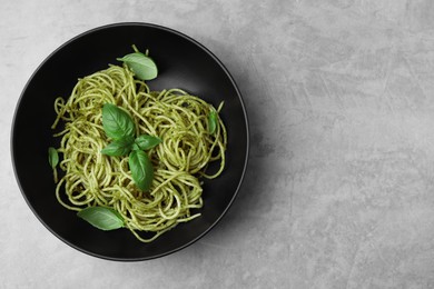 Photo of Delicious pasta with pesto sauce and basil on light grey table, top view. Space for text