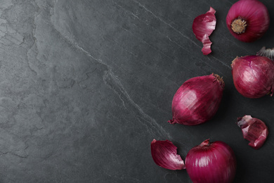 Ripe red onion bulbs on black table, flat lay. Space for text