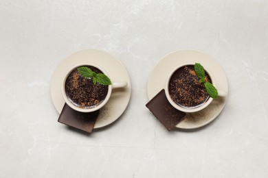 Photo of Cups of delicious hot chocolate with fresh mint on grey table, flat lay