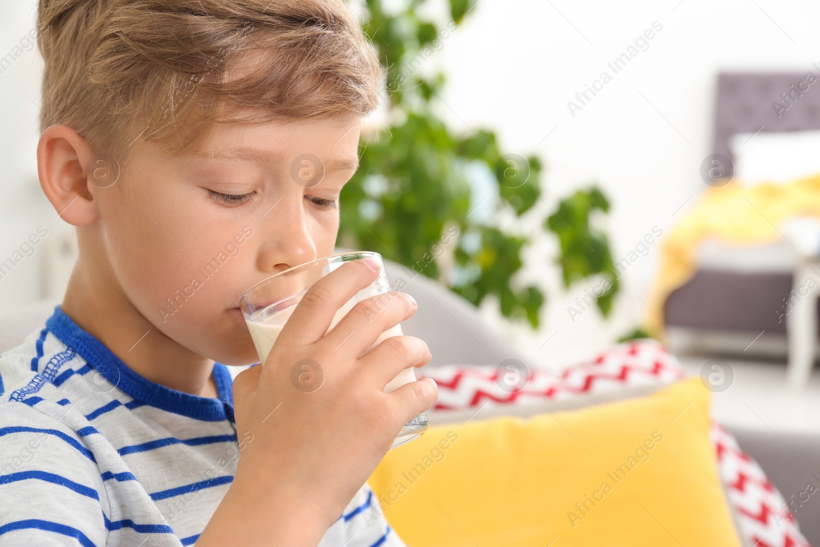 Photo of Adorable little boy with glass of milk at home