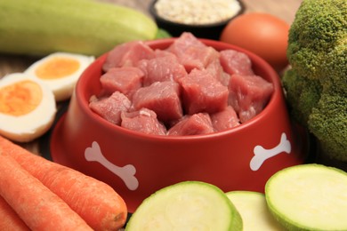Photo of Raw meat in bowl and healthy products for pet on table, closeup