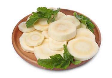 Cut fresh ripe parsnip with leaves in wooden plate on white background