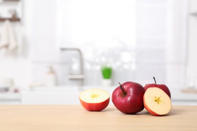 Whole and cut apples on wooden counter in kitchen, space for text