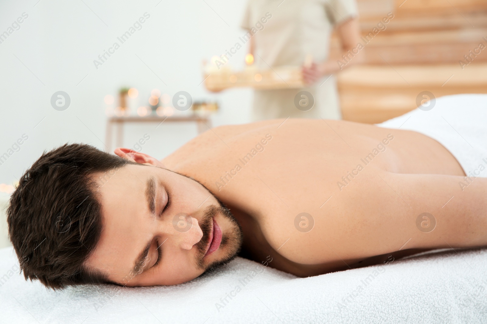 Photo of Handsome man relaxing on massage table in spa salon