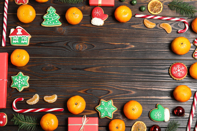 Photo of Frame made with tasty Christmas cookies and tangerines on wooden background, flat lay. Space for text
