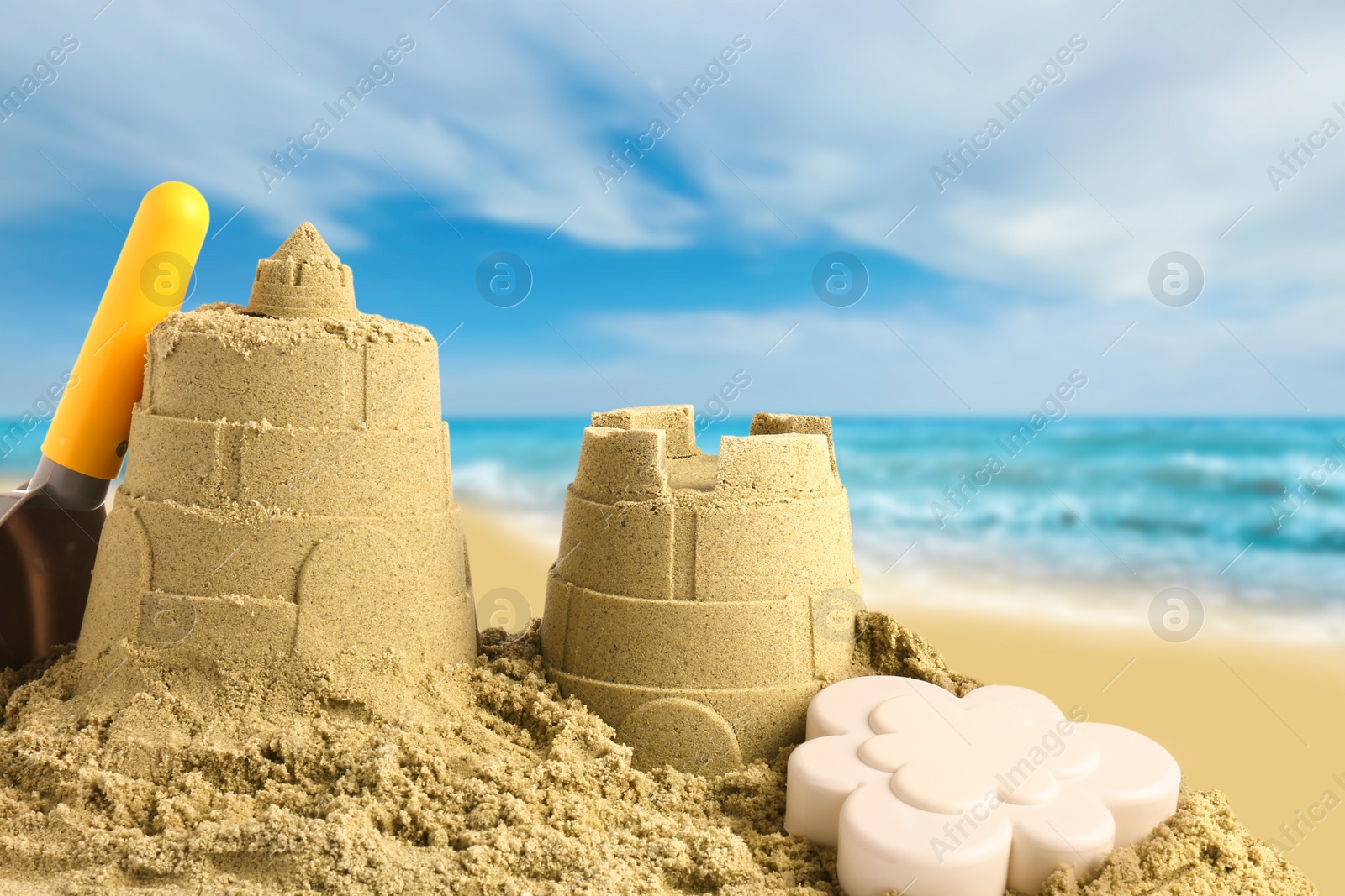 Image of Sand castles with toys on ocean beach, closeup. Outdoor play