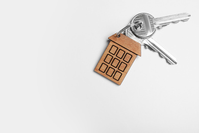 Photo of Keys with trinket in shape of house isolated on white, top view. Real estate agent services