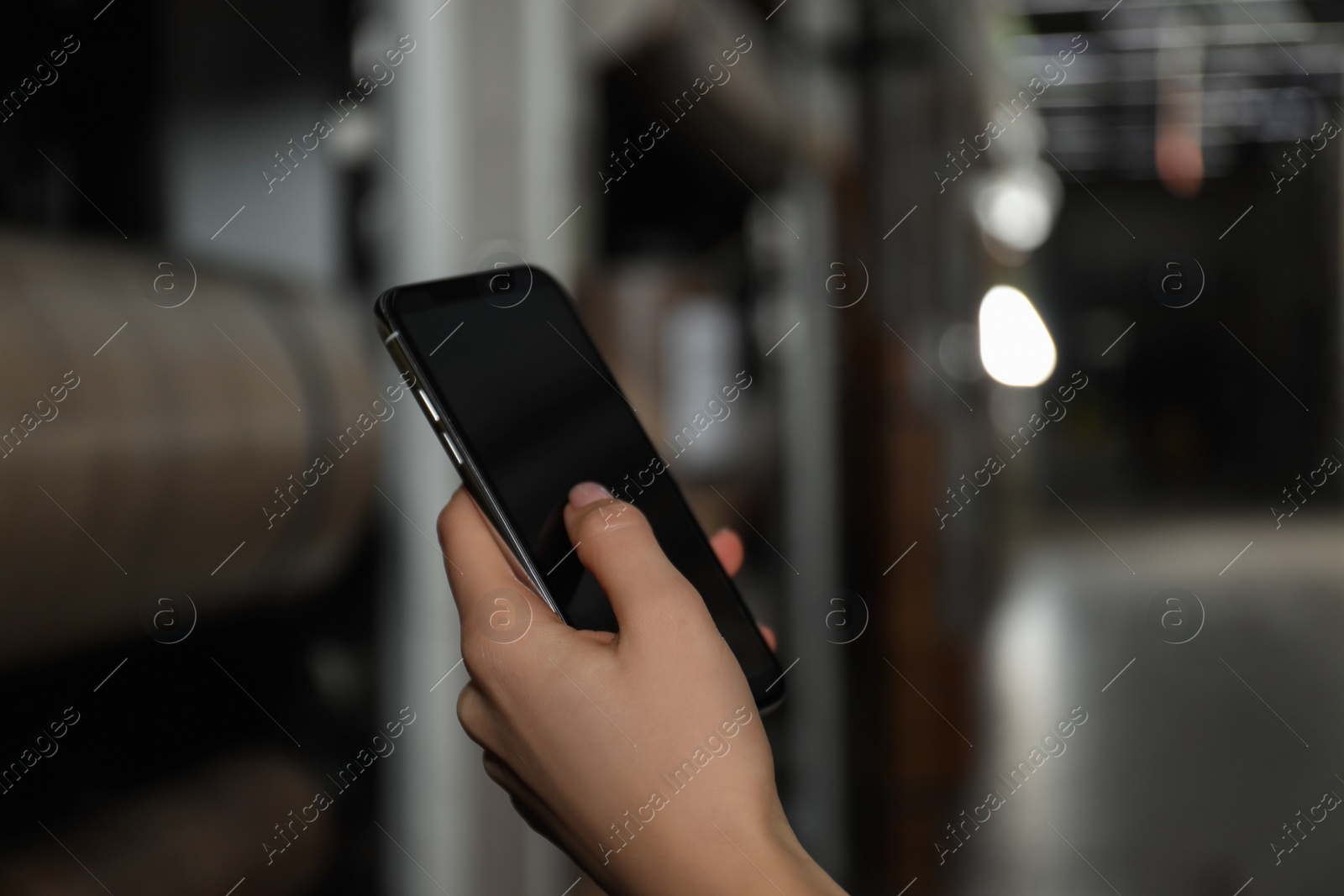 Photo of Woman with smartphone in wholesale warehouse, closeup. Space for design