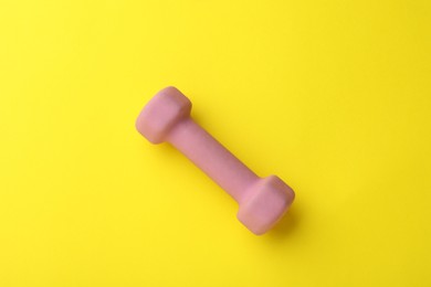 Photo of Stylish dumbbell on yellow background, top view