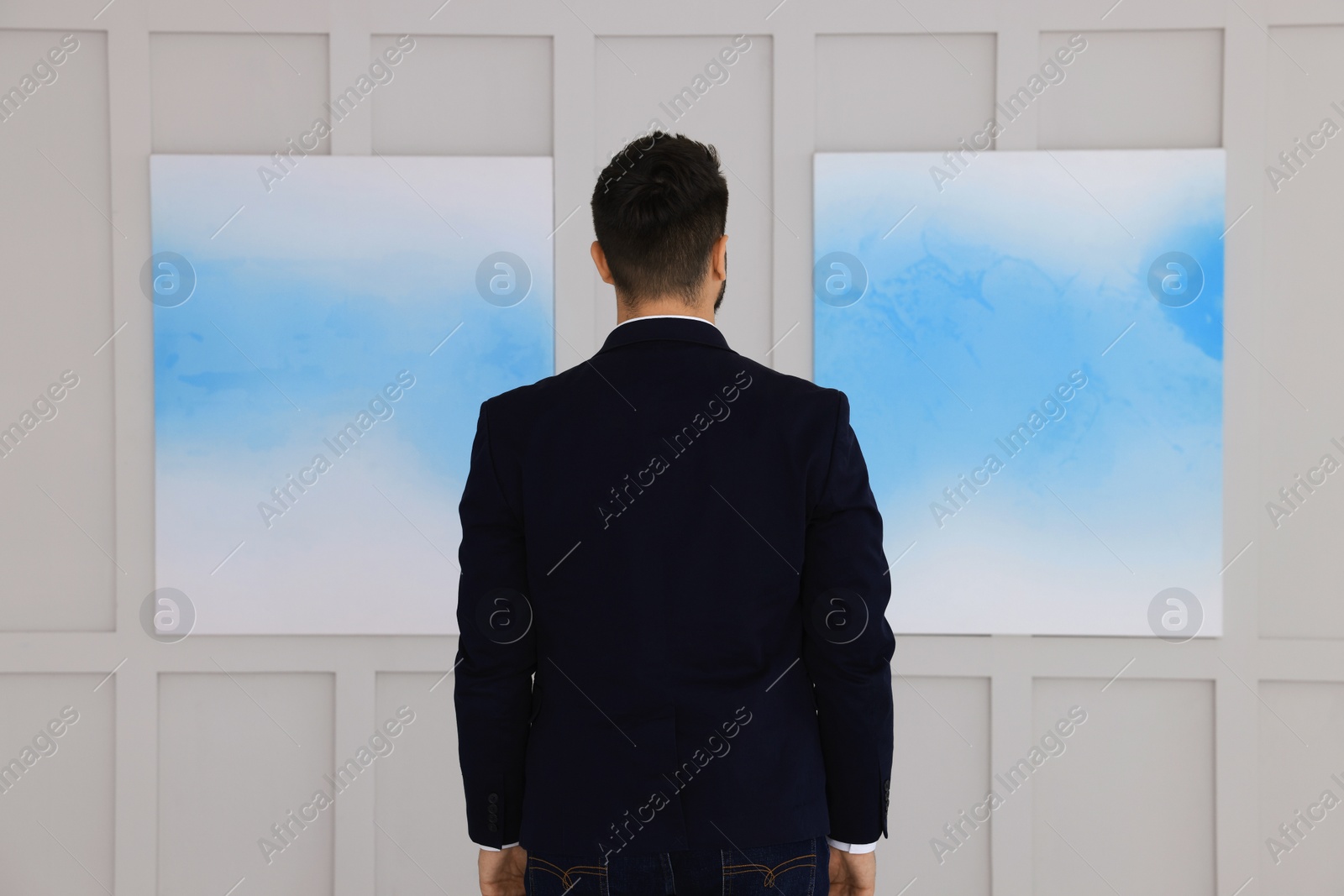 Photo of Young man at exhibition in art gallery, back view