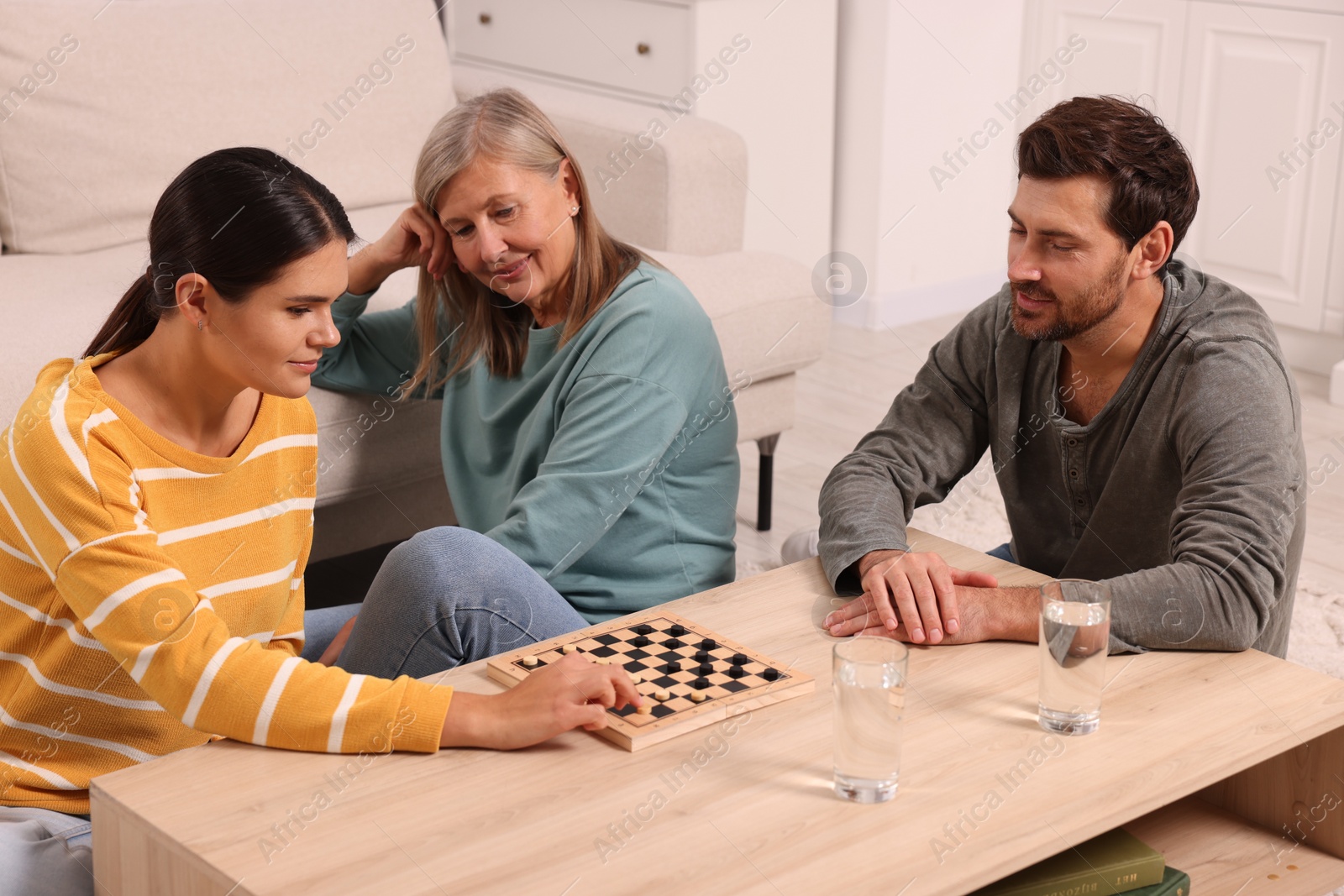 Photo of Family playing checkers at wooden table in room