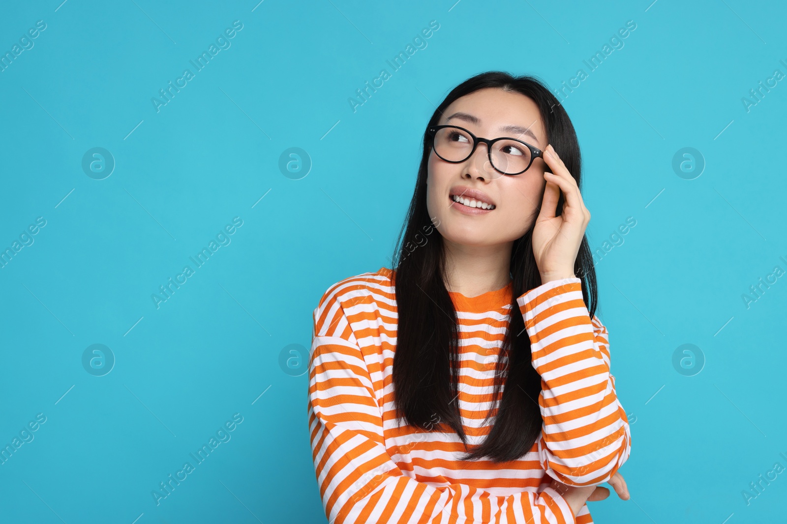 Photo of Portrait of happy woman in glasses on light blue background. Space for text