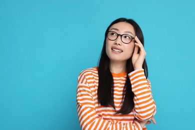 Photo of Portrait of happy woman in glasses on light blue background. Space for text