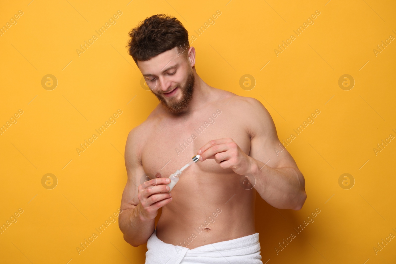 Photo of Handsome man with serum on orange background