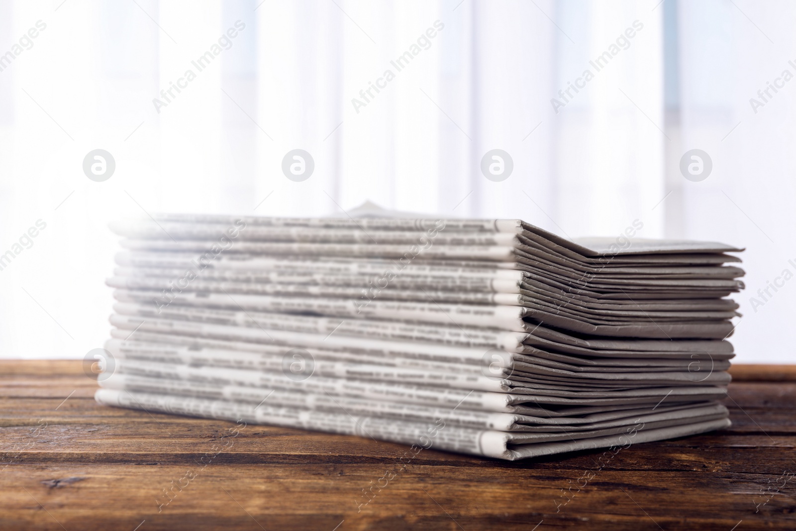 Image of Stack of newspapers on wooden table. Journalist's work