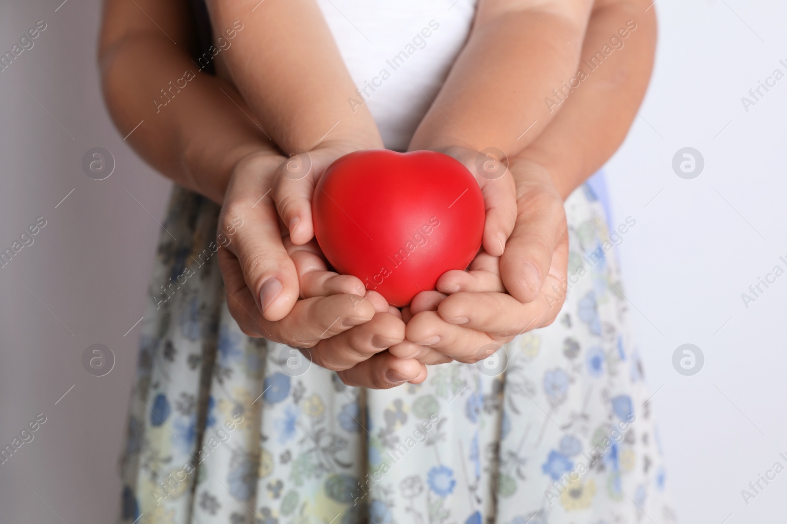 Photo of Adult and child hands holding heart on light background, closeup. Family concept
