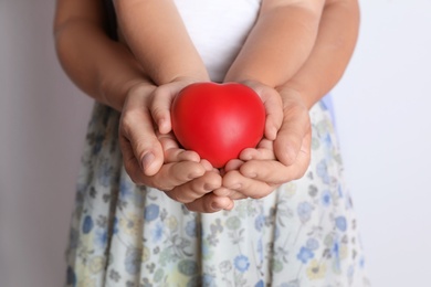 Photo of Adult and child hands holding heart on light background, closeup. Family concept