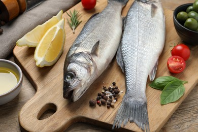 Photo of Sea bass fish and ingredients on wooden table, closeup