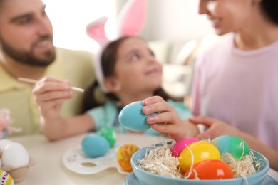 Photo of Happy family painting Easter eggs at table indoors, focus on hand