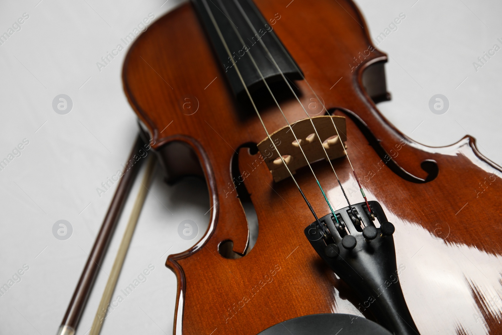 Photo of Beautiful violin and bow on grey stone table, closeup
