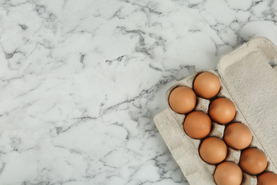 Raw chicken eggs on white marble table, top view. Space for text