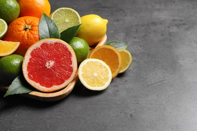 Photo of Different citrus fruits on black table, closeup. Space for text