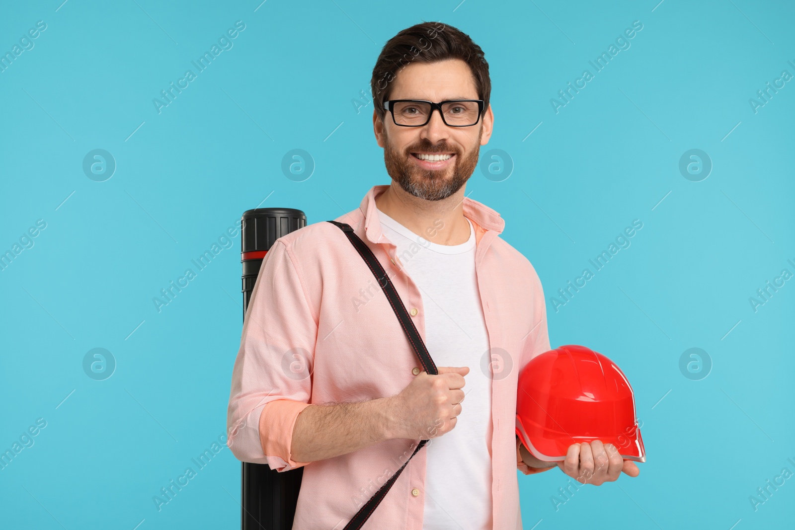 Photo of Architect with drawing tube and hard hat on light blue background