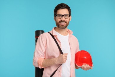 Photo of Architect with drawing tube and hard hat on light blue background