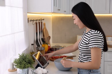 Photo of Cooking process. Woman searching recipe on tablet in kitchen