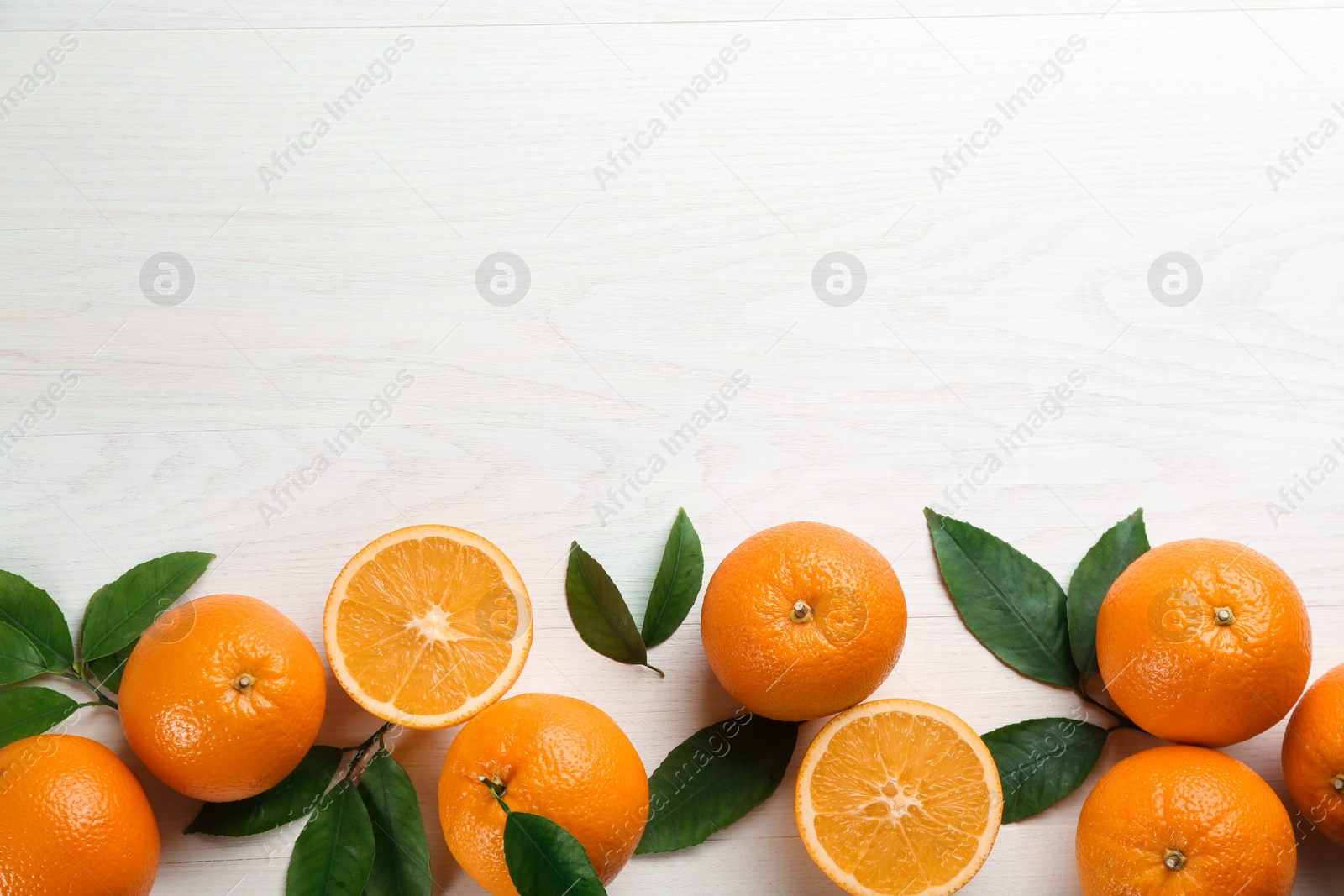 Photo of Delicious ripe oranges on white wooden table, flat lay. Space for text