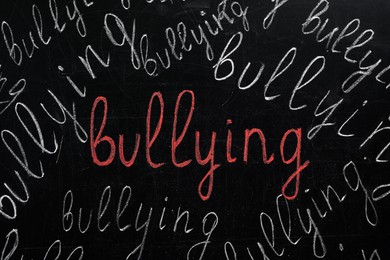 Photo of Many words Bullying written on blackboard, closeup view