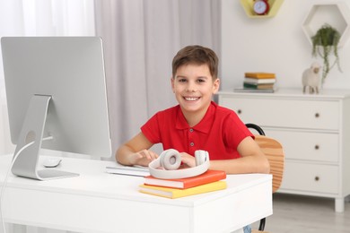 Boy using computer at desk in room. Home workplace